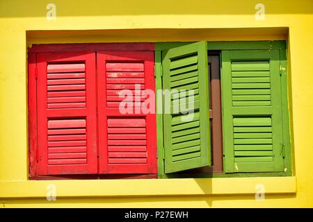 Vista frontale della vendemmia tradizionale Singapore negozio Casa con arredi di colore rosso e verde persiane di legno su un esterno giallo nella storica Little India. Foto Stock