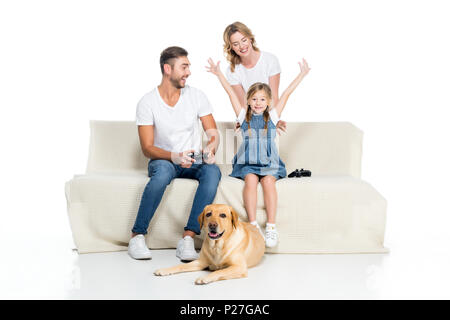 Famiglia eccitato la riproduzione del video gioco con joystick mentre dog sitter vicino, isolato su bianco Foto Stock