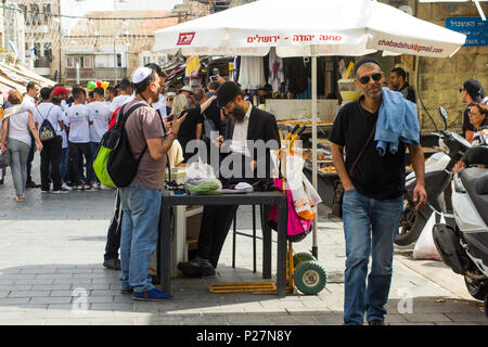 9 maggio 2018 un gruppo di ebrei uomini chiacchierare insieme sotto una pantina parasole in Mahane Yehuda street market in Jerusalem Israel Foto Stock