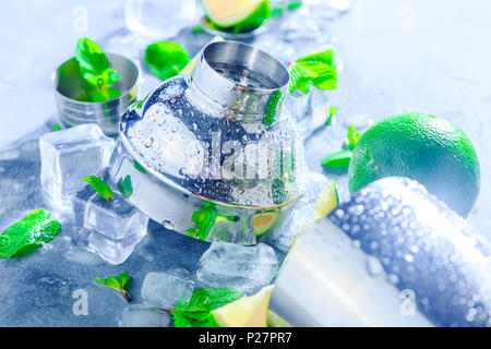 Shaker e accessori bar close-up. Cocktail Mojito ingredienti, menta, calce e cubetti di ghiaccio su una pietra grigia sullo sfondo. Bevanda estiva concetto con copia Foto Stock