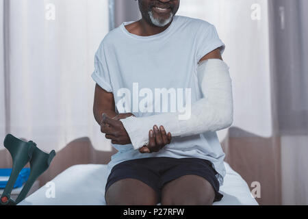 Immagine ritagliata di African American paziente con braccio rotto nel calco in gesso Foto Stock