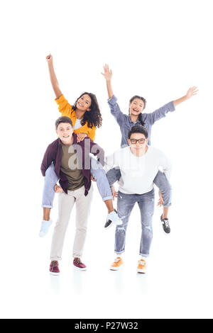 Felice interracial teen amici piggybacking insieme isolato su bianco Foto Stock