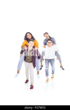 Felice interracial teen amici piggybacking insieme isolato su bianco Foto Stock