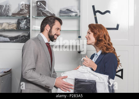 Lavaggio a secco direttrice dando borsa con abiti da uomo felice Foto Stock