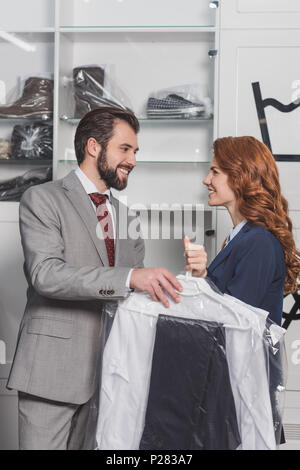 Lavaggio a secco direttrice dando borsa con abiti da uomo bello Foto Stock