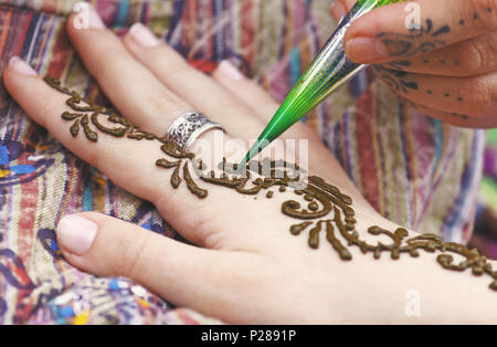 Artista pittura tradizionale indiana henna tattoo sulla donna mano, primo piano immagine, concentrarsi su mehndi artwork Foto Stock