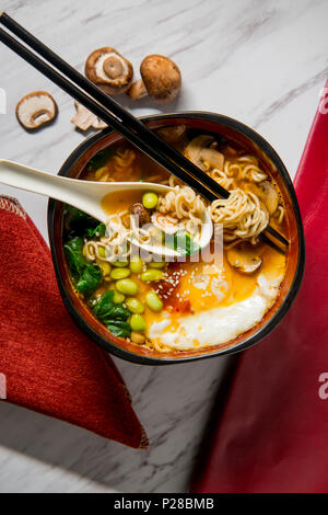 Edamame piccante e spirale narutomaki ramen noodle soup con naso che cola uovo fritto Foto Stock