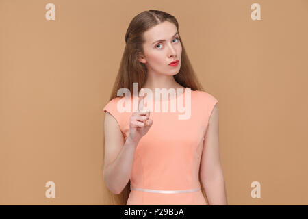 Donna seious allarmante come un boss. ritratto emotiva di carino, bella donna con il trucco e capelli lunghi in abito rosa. indoor, studio shot, isolato Foto Stock