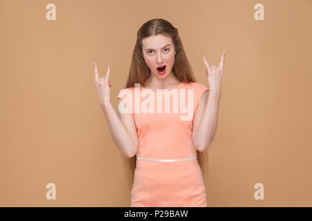 Rock and Roll. sorpreso ragazza con bocca aperta. ritratto emotiva di carino, bella donna con il trucco e capelli lunghi in abito rosa. indoor, studio shot Foto Stock