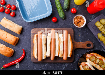 Foto sulla parte superiore di due hotdog sul bordo di taglio sul tavolo con salsicce Foto Stock