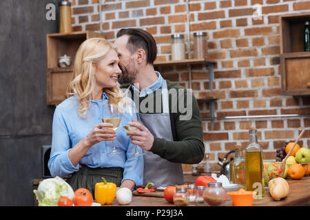 Il marito e la moglie tintinnanti con bicchieri di vino in cucina Foto Stock