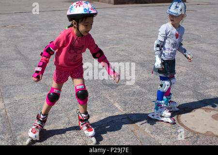 Due piccoli cute ragazze impara pattinaggio sulla strada di città Foto Stock