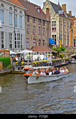 Uno dei molto popolari battelli prende un gruppo di turisti e visitatori in un tour del canale del centro di Bruges o Brugge, Belgio Foto Stock