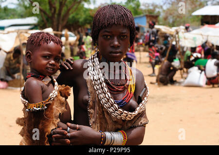 TURMI, Valle dell'Omo, Etiopia - 29 luglio 2013: Ritratto di donna con il piccolo bambino sulla mano da Hamer persone sul mercato locale in Turmi Foto Stock