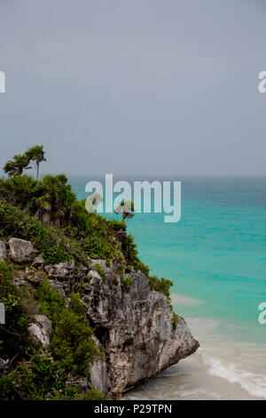 Anche in una giornata di pioggia, acque turchesi e affioramenti rocciosi di Tulum sono accattivanti. Foto Stock