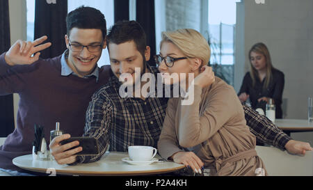 Gruppo di sorridenti persone prendendo un autoritratto in un caffè mentre avente una pausa Foto Stock