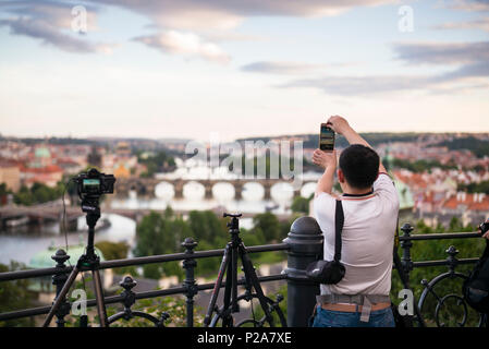 Praga. Repubblica ceca. Tourist utilizzando un telefono cellulare per scattare foto della vista dal parco Letná che fornisce un punto di vista del fiume Moldava e l'O Foto Stock