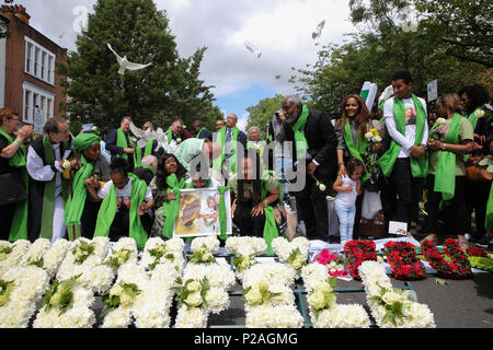 A ovest di Londra. Londra. Regno Unito 14 Giugno 2018 - processione silenziosa da St Helen's Chiesa, North Kensington alla base della torre Grenfell fuori Kensington Leisure Centre dopo colombe bianche sono state rilasciate dai membri della famiglia. Membri della famiglia lay ghirlande di fiori e la accensione di candele alla base della torre Grenfell fuori Kensington il centro per il tempo libero. L incendio è scoppiato il 14 giugno 2017 in 24 piani di Grenfell a torre dell'edilizia pubblica appartamenti nel Nord di Kensington, West London, in cui 72 persone hanno perso la loro vita. Credito: Dinendra Haria/Alamy Live News Foto Stock