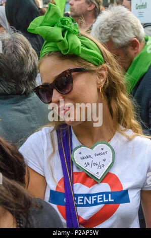 Londra, Regno Unito. 14 giugno 2018. Una donna che indossa un cuore con il messaggio "Mai dimenticare 16/06/17 ' nella folla di migliaia di persone in attesa di camminare in silenzio da vicino alla Torre Grenfell ricordando le vittime del disastro nel primo anniversario del disastroso incendio che ha ucciso 72 e lasciato superstiti traumatizzati. Molte di quelle rese senzatetto dal fuoco sono ancora in un alloggio temporaneo di un anno più tardi, nonostante le promesse mde di Theresa Maggio e a Kensington & Chelsea consiglio che molti caddero hanno fallito la comunità locale sia prima e dopo l'incendio. Dicono che se fossero stati ascoltati e rispettati Gren Foto Stock