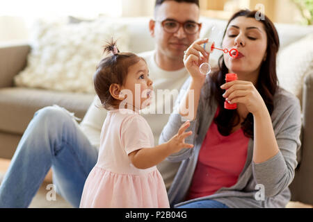 Famiglia con bolle di sapone a giocare a casa Foto Stock