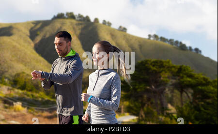 Giovane con fitness trackers correndo all'aperto Foto Stock