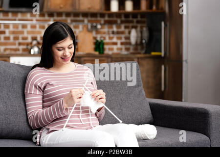 Bella sorridente giovane donna incinta maglia a casa Foto Stock