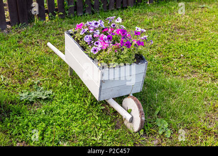 Giardino in legno carrello con fiori decorativi sull'erba verde Foto Stock