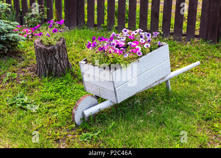 Giardino in legno carrello con fiori decorativi sull'erba verde Foto Stock
