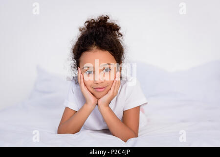 Adorable African American kid mento di appoggio sulle mani a casa Foto Stock