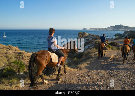 I turisti a cavallo, equitazione da San Jose sulla costa rocciosa di Cabo de Gata nel pomeriggio, provincia di Almeria, Andalus Foto Stock