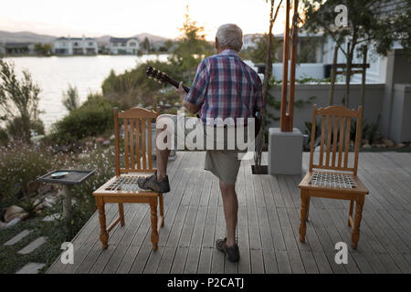 Senor uomo a suonare la chitarra nel portico Foto Stock