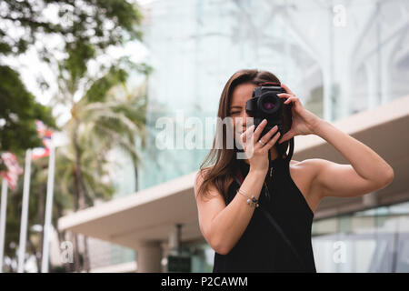 Donna facendo clic su una foto con una fotocamera digitale Foto Stock