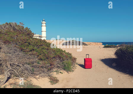 Valigia rossa su un percorso al faro di Cap de Ses Salines. Messa a fuoco selettiva Foto Stock