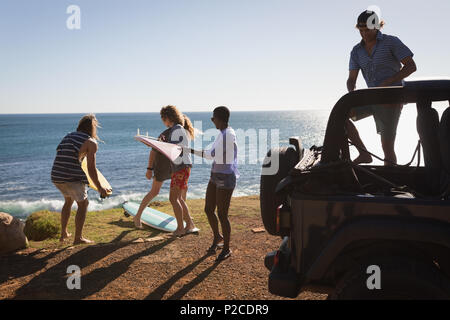 Gruppo di amici rimuovendo le tavole da surf da jeep Foto Stock