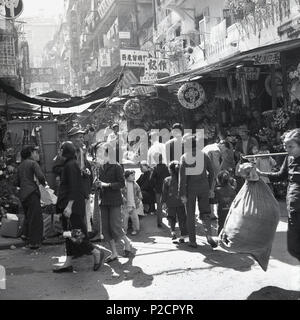 1950, storico, persone fuori in una strada trafficata nella città vecchia, Hong Kong mostrando bancarelle all'aperto, commercianti e alloggi viventi sopra. Foto Stock