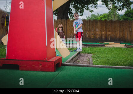 Una giovane ragazza gioca golf in miniatura nelle giornate più calde. Foto Stock