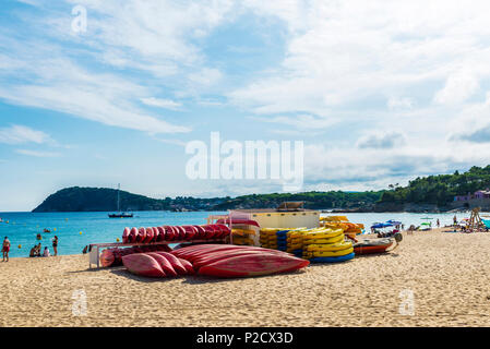 Palamos, Spagna - Luglio 10, 2017: Heap di giallo, rosso e blu kayak o barche di plastica con la gente la balneazione su un Castell Spiaggia di Palamos, Costa Brav Foto Stock