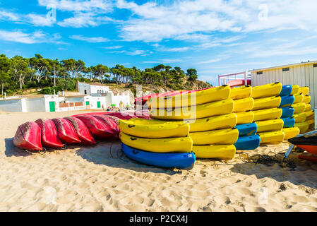 Girona, Spagna - 10 Luglio 2017: Heap di giallo, rosso e blu kayak o barche di plastica su una spiaggia di Palamos, in Costa Brava Girona, in Catalogna, Spagna Foto Stock