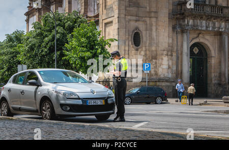 Braga, Portogallo - 23 Maggio 2018: controlli di poliziotto e scrive un biglietto di traffico su un auto nel centro della città in un giorno di primavera Foto Stock