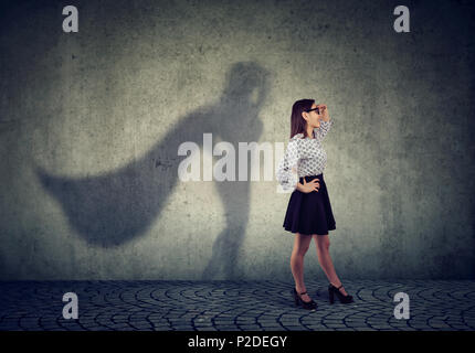 Vista laterale di una donna d'affari di immaginare di essere un super eroe cerca aspirava. Foto Stock