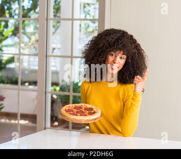 African American donna pronto a mangiare una gustosa salsiccia per pizza pizza a casa molto felice rivolto con la mano e le dita per lato Foto Stock