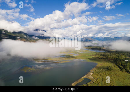 Nuvole bianche sul lago immerso nel verde paesaggio Foto Stock