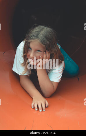 Bambina si arriva al di fuori del tunnel al parco giochi Foto Stock