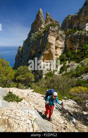 Una giovane donna con ingranaggio trekking escursioni lungo la costa di montagna sopra il mare del Golfo di Orosei, Selvaggio Blu, Sardegna, Ita Foto Stock