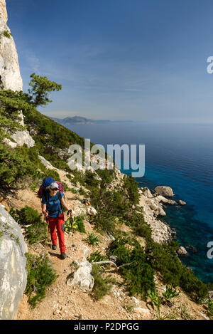 Una giovane donna con ingranaggio trekking escursioni lungo la costa di montagna sopra il mare del Golfo di Orosei, Selvaggio Blu, Sardegna, Ita Foto Stock