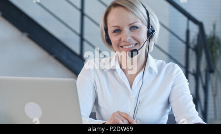 Bella Donna sorridente con cuffie guardando la fotocamera Foto Stock
