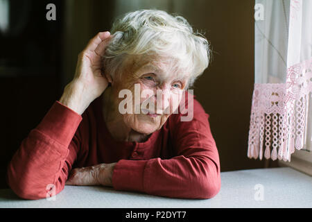 Una donna anziana ascolta con la sua mano al suo orecchio. Problemi di udito, seniors perdita di udito. Foto Stock
