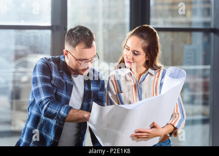 Maschi e femmine di ingegneri guardando blueprint e discutere di progetto Foto Stock