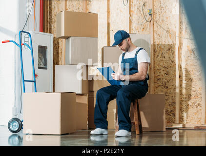 Uomo del caricatore il riempimento di dichiarazione di merci da pile scatole Foto Stock