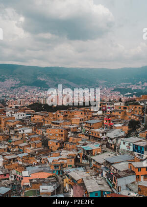 La proliferazione incontrollata di brezza case di blocco del famoso Comuna 13 incontra il cielo raschiatori del centro della città di Medellin, Colombia Foto Stock